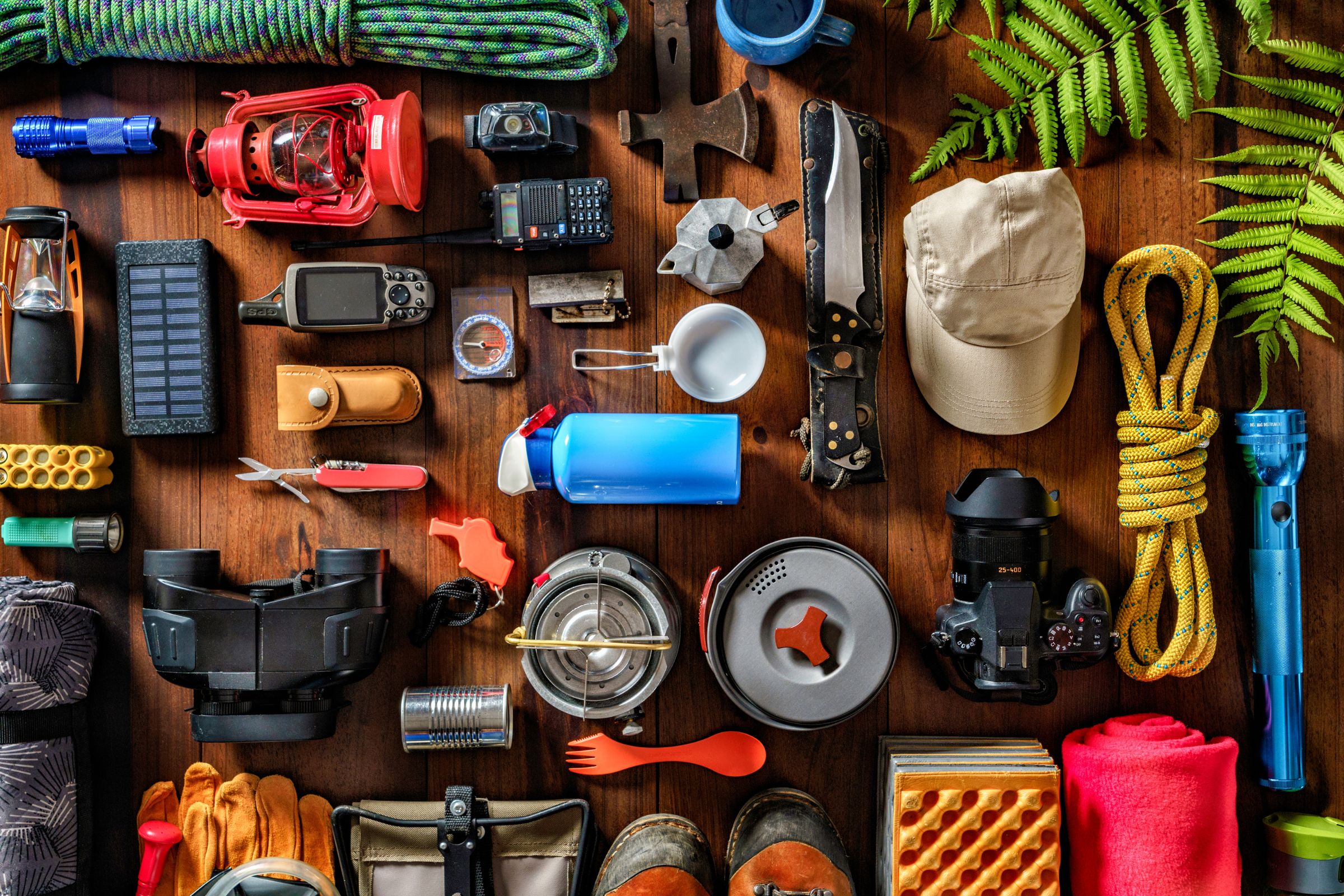 Essential camping gear, including lanterns, ropes, knives, a compass, water bottles, cookware, flashlights, and outdoor tools.