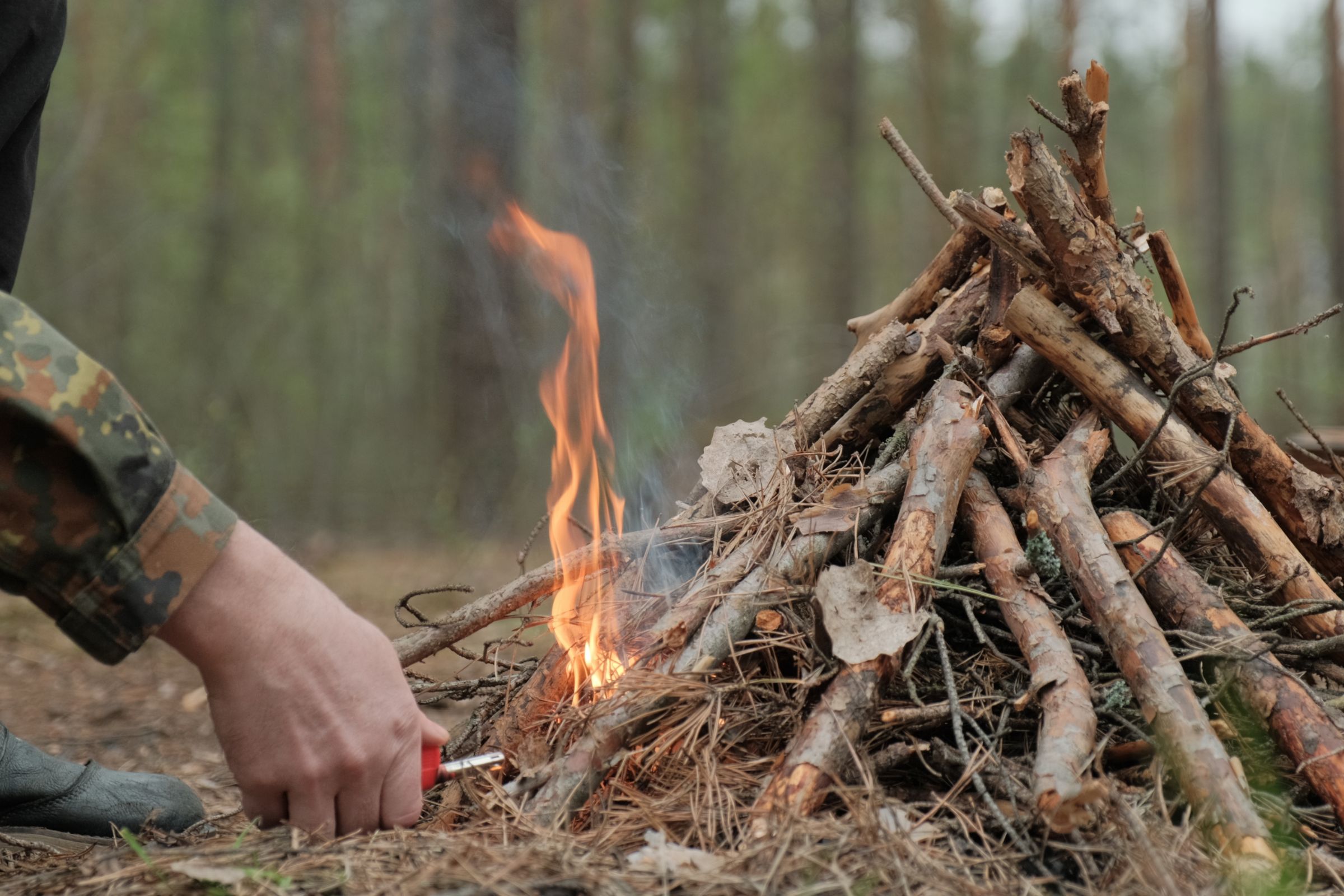 ExploreGear.com | Fire starting technique using twigs in forest survival.