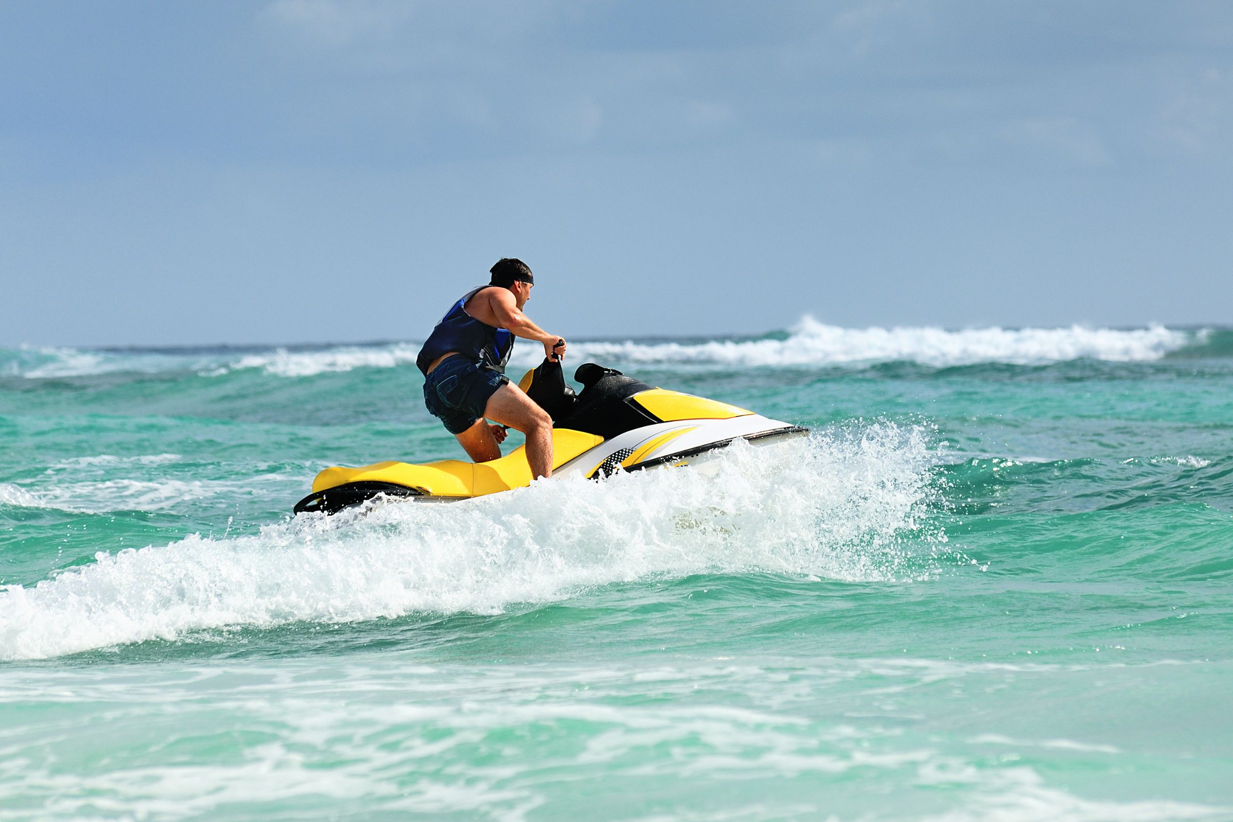 ExploreGear.com | Man riding yellow jet ski in turquoise waters.