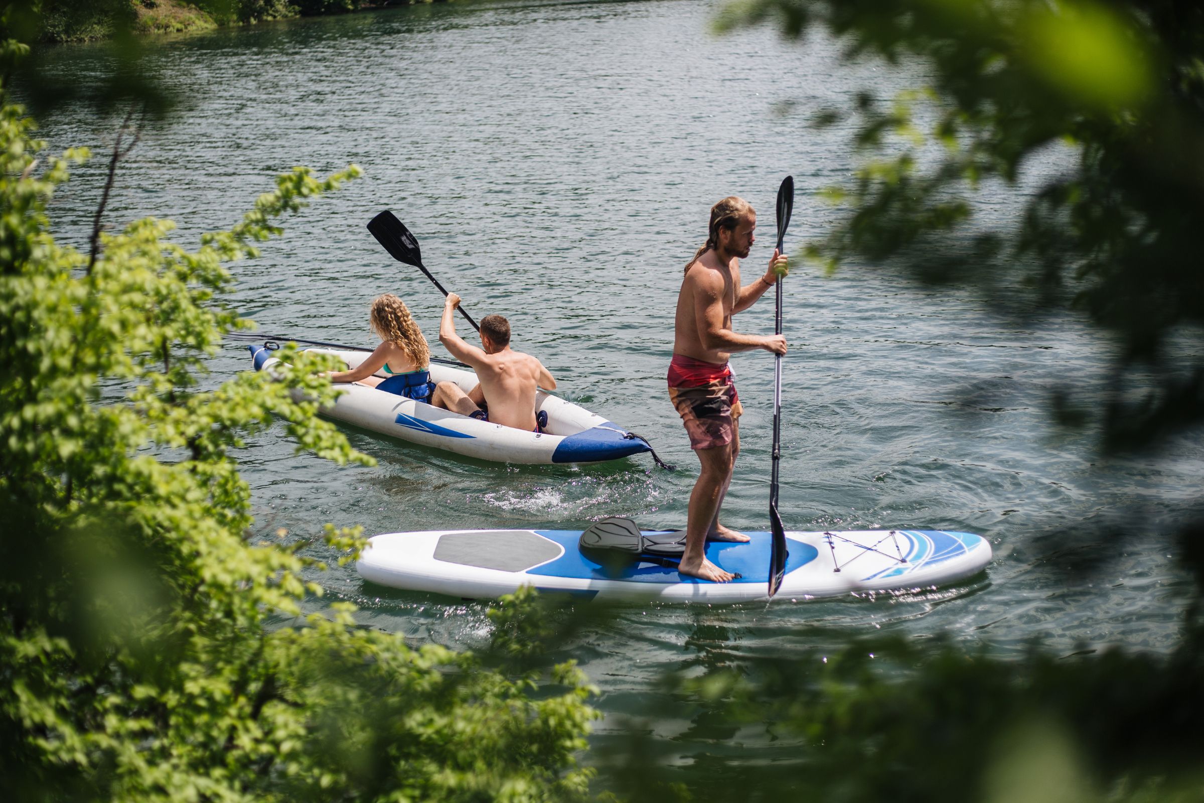 ExploreGear.com | People kayaking and paddleboarding on a serene lake.