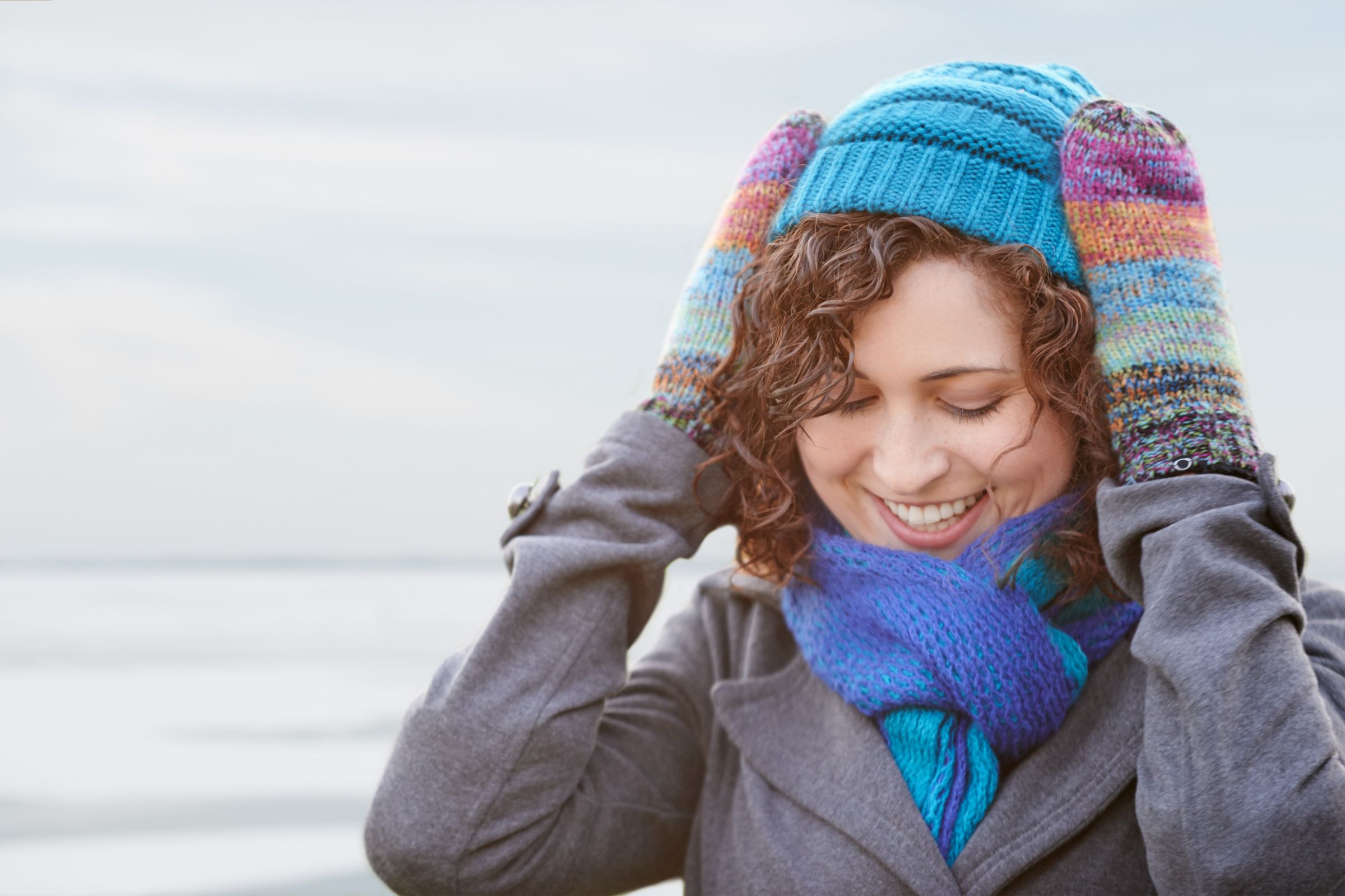 ExploreGear.com | Woman smiling in winter attire with colorful mittens