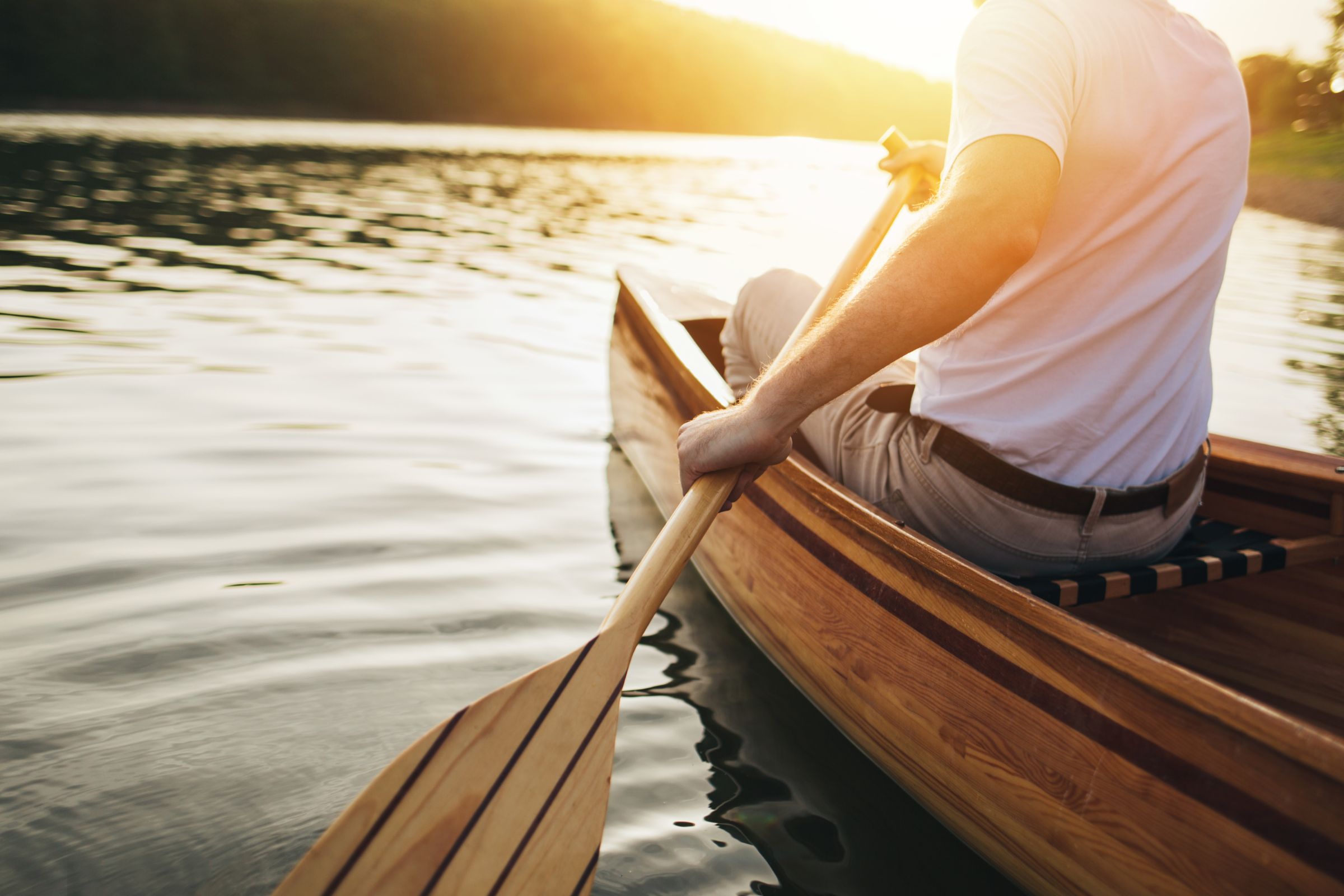 ExploreGear.com | Canoeing at sunset with wooden paddle on calm water