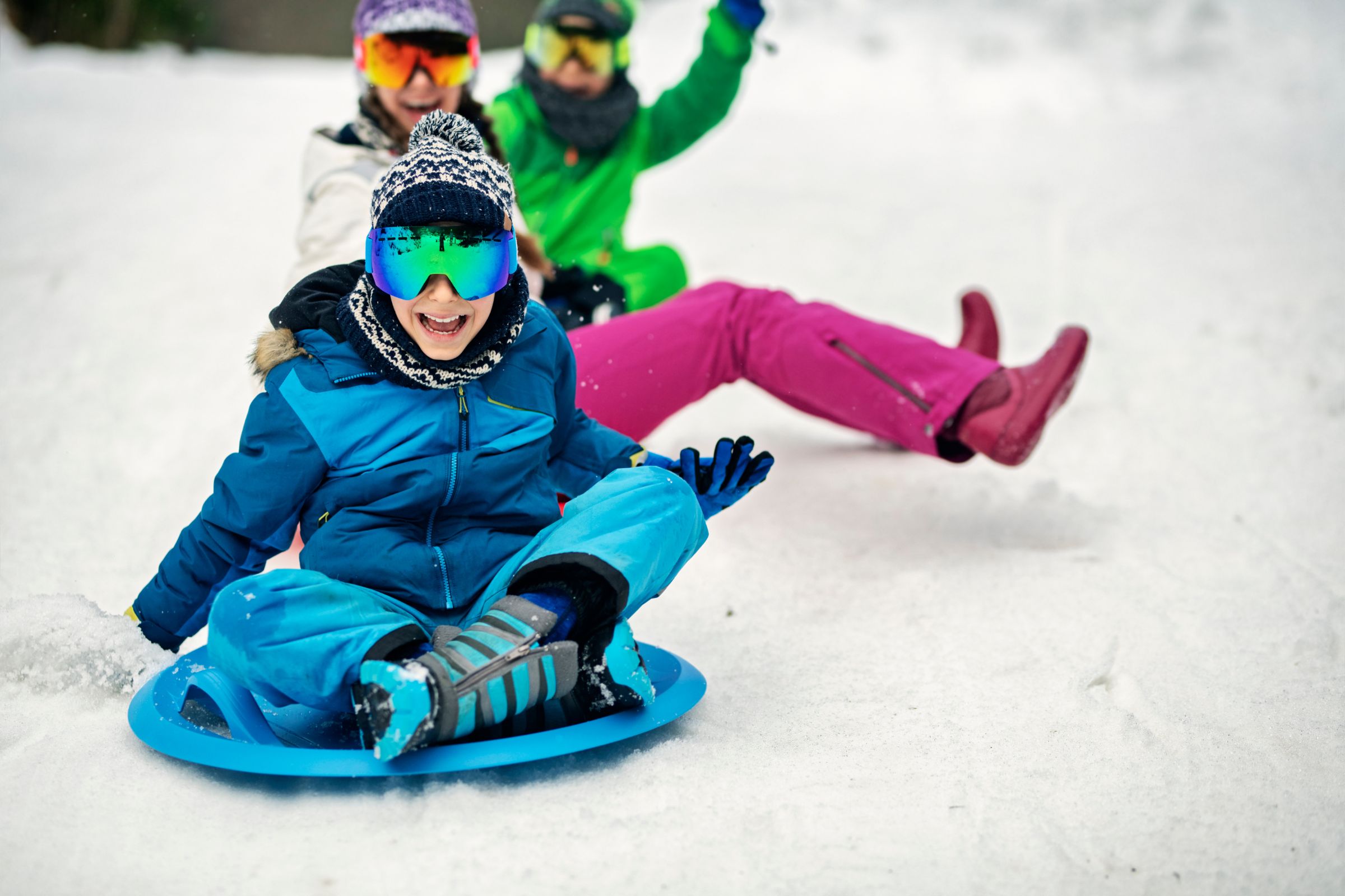 ExploreGear.com | Kids enjoying sledding fun with safety gear outdoors