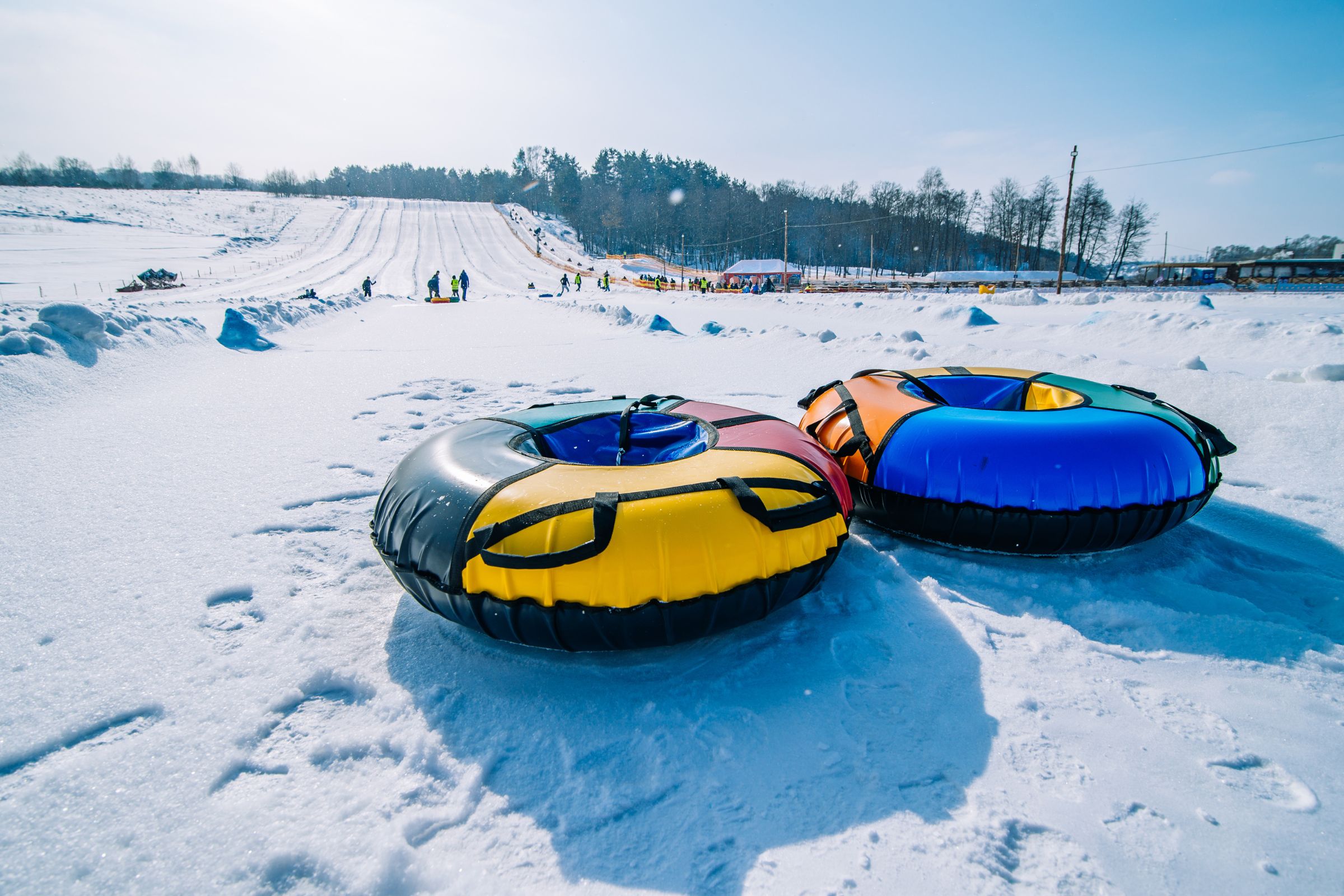 ExploreGear.com | Colorful snow tubes on slopes under sunny sky.