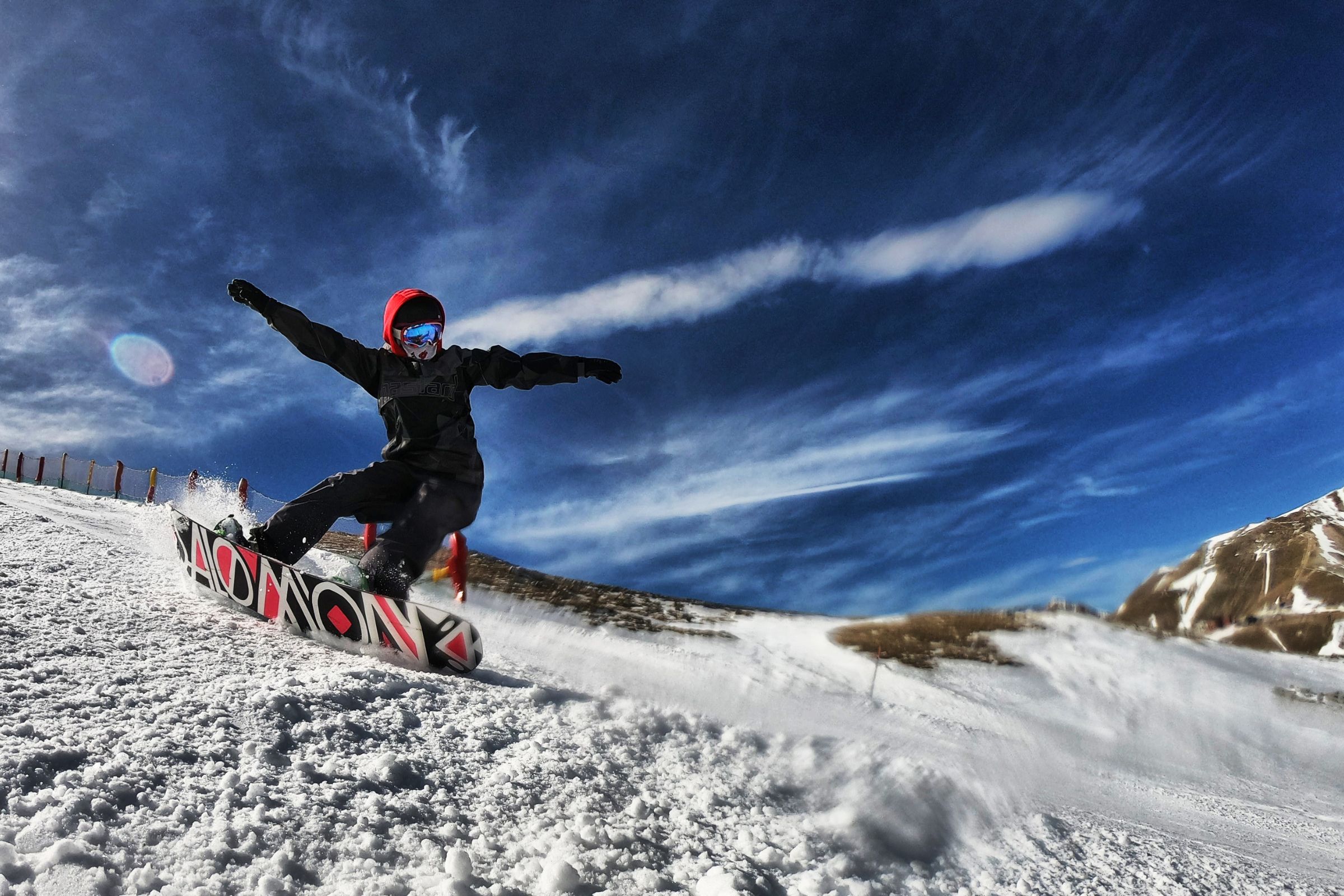 ExploreGear.com | Snowboarder performing tricks under a bright blue sky.