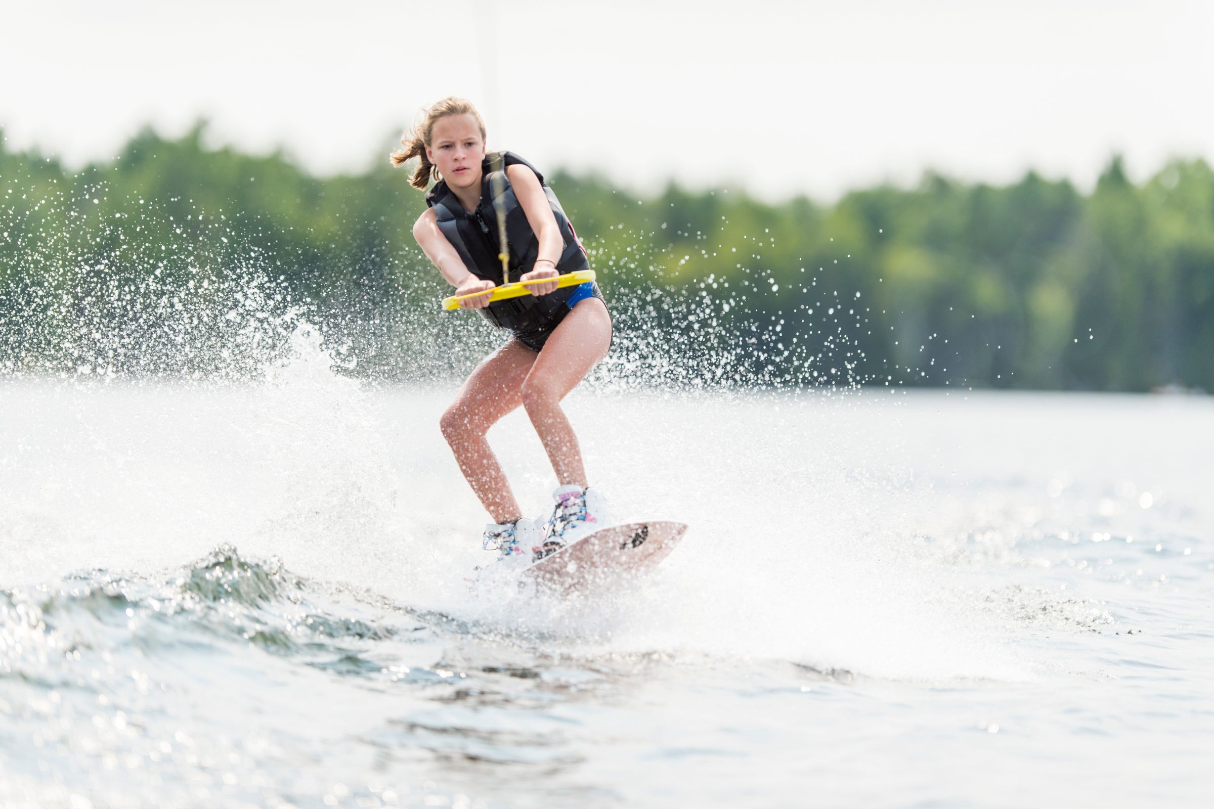 ExploreGear.com | Girl wakeboarding, practicing basic tricks on a lake.